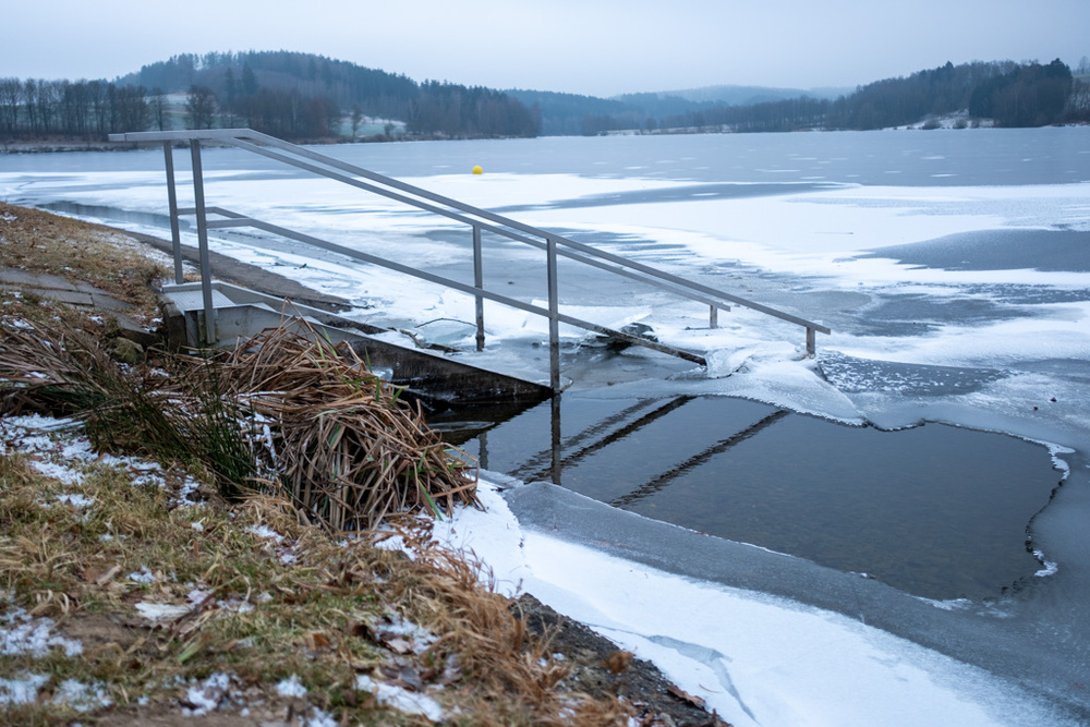 Reflektion einer Treppe in den See, rund herum schon Eis.